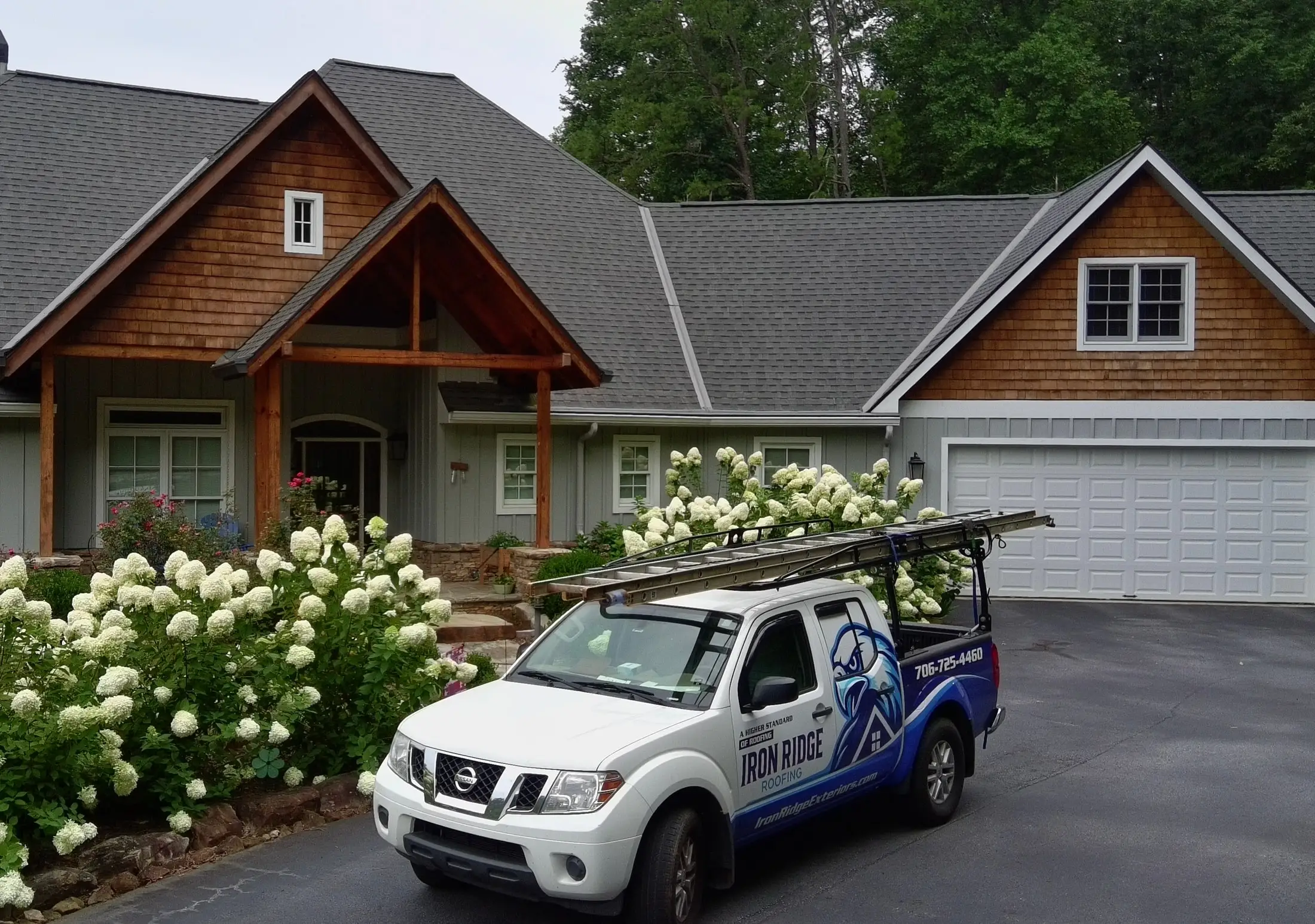 Iron Ridge Roofing truck in front of a craftsman-style home with a new gray shingle roof
