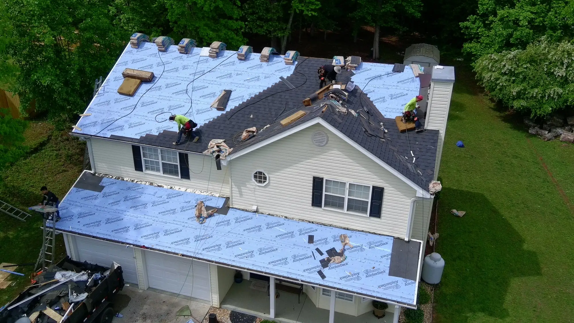 Iron Ridge crew installing new shingles over fresh underlayment on a two-story home