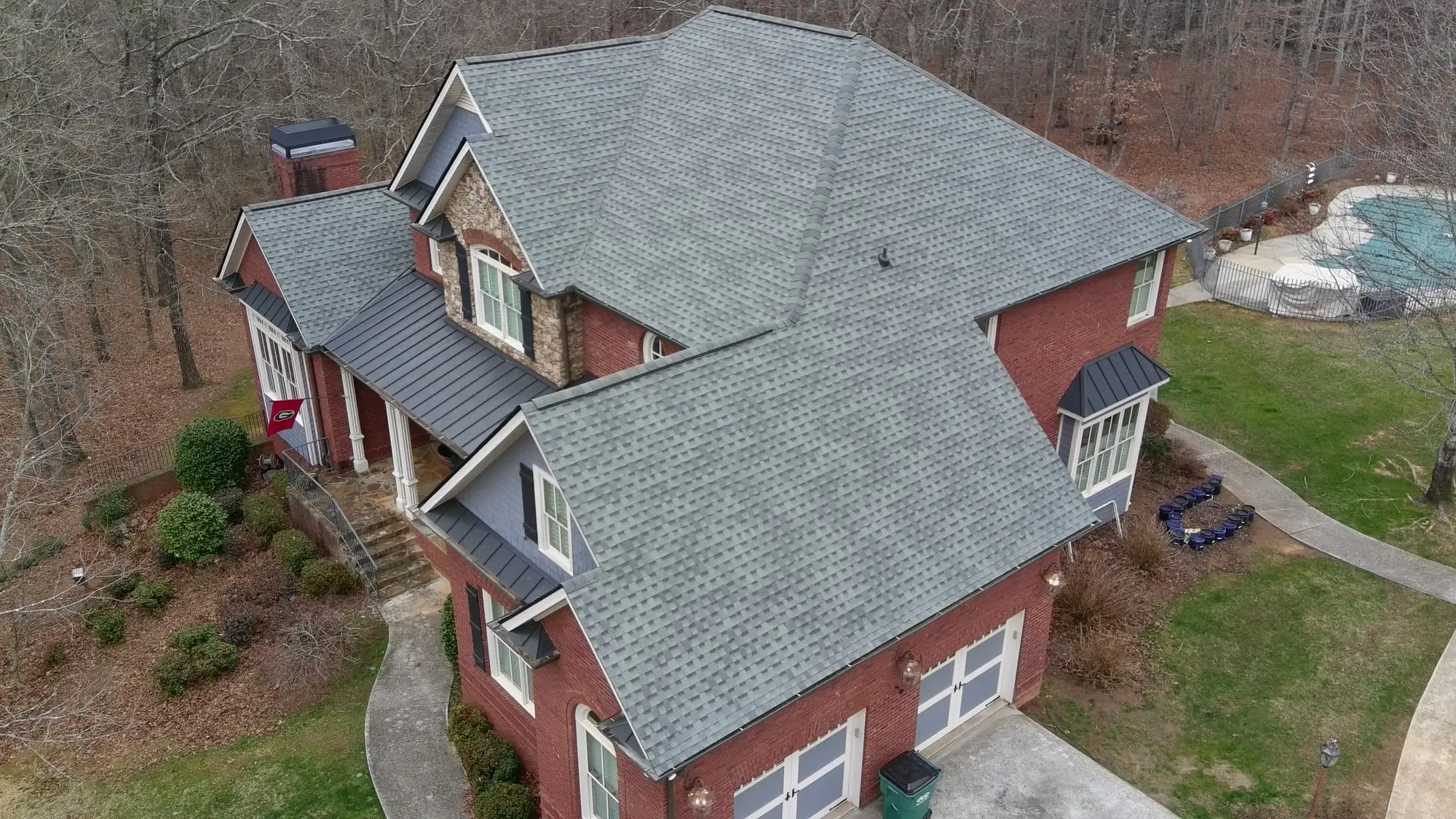 Brick and stone home with a new gray architectural shingle roof installed by Iron Ridge Roofing