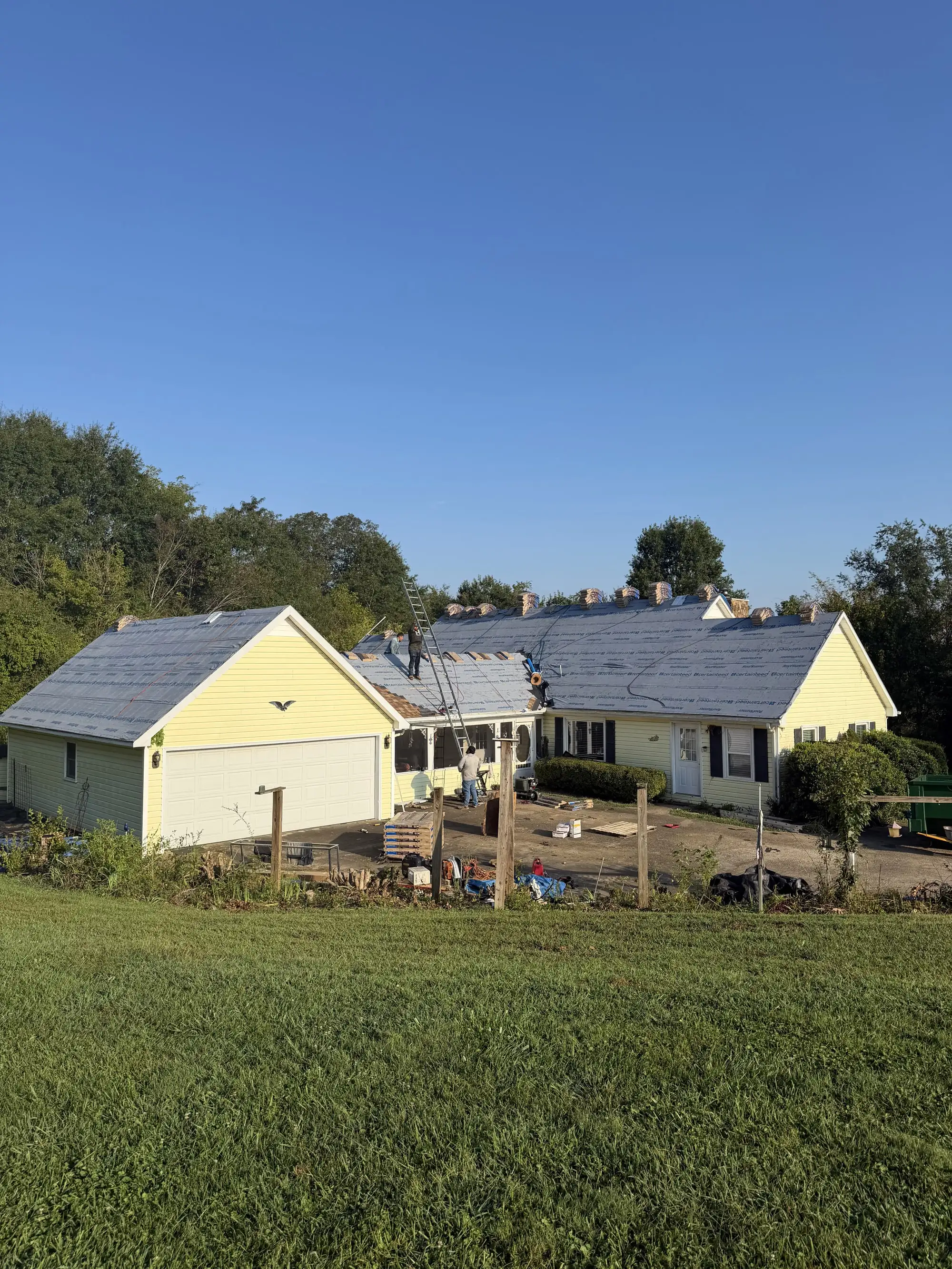 Iron Ridge crew installing a new roof on a yellow ranch-style home