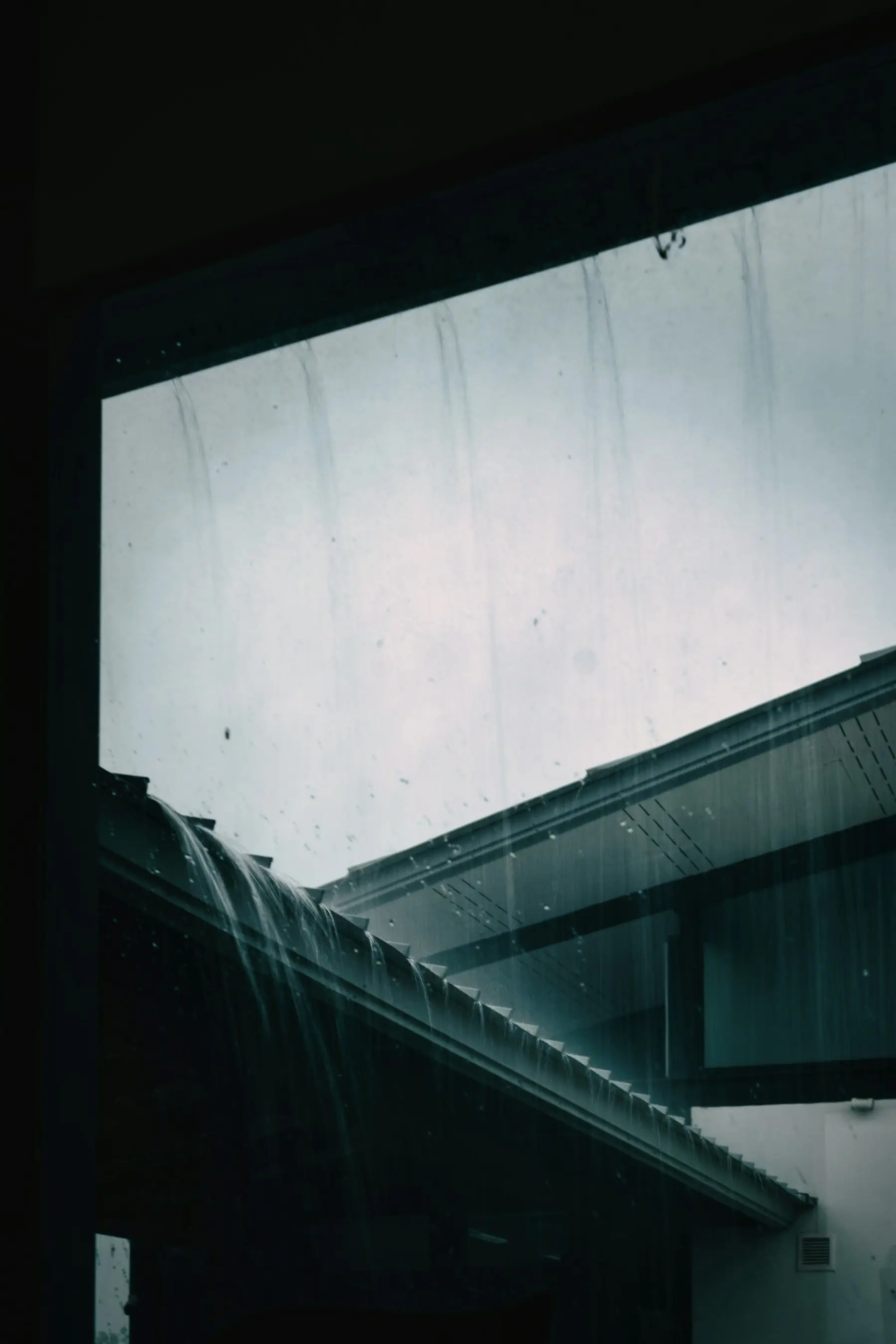 Heavy rain pouring off the edge of a roof